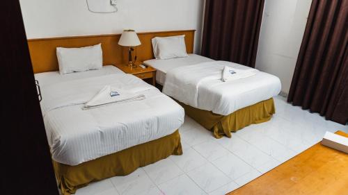 a hotel room with two beds and a lamp at Pan Emirates Hotel Apartments in Sharjah
