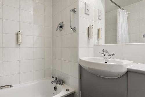 Days Inn Bridgend Cardiff في بريدجيند: حمام أبيض مع حوض وحوض استحمام