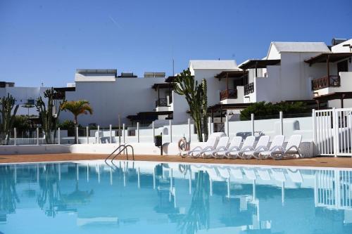 einen Pool mit Stühlen und Gebäuden im Hintergrund in der Unterkunft CASA VELA by Mhousing in Playa Blanca