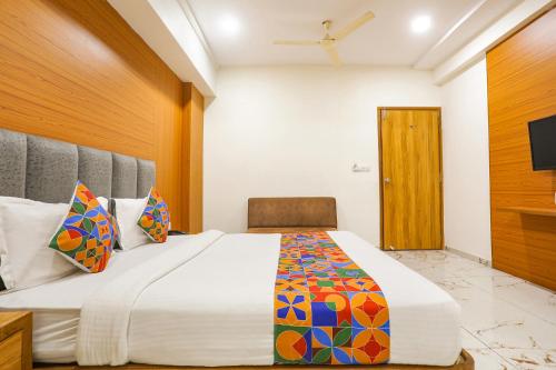 a bedroom with a large bed and a chair at FabHotel Raj Villa - Nr Tri mandir in Jāmb
