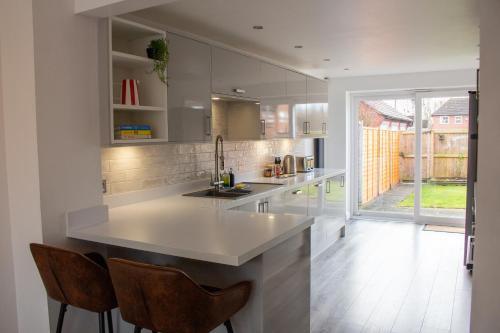 a kitchen with a large white counter and chairs at 4 Bedroom House-Sleeps 8-Parking in Devizes