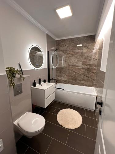 a bathroom with a toilet and a tub and a sink at Sunrise apartment in Baia Mare