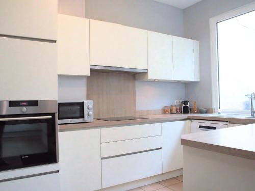 une cuisine avec des armoires blanches et un micro-ondes dans l'établissement La Vue Cathédrale - Grande maison en hypercentre, Idéal Groupe, à Saint-Omer