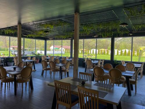 a restaurant with tables and chairs and windows at Green Resort Suncuius in Şuncuiuş
