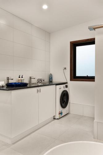 a white kitchen with a washing machine and a window at Hidden Retreat in Royal Park