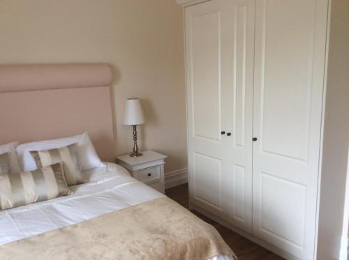 a bedroom with a white bed and a white closet at St Columbs House in Buncrana