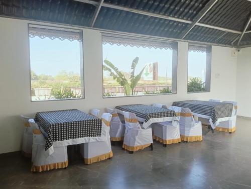 two tables and chairs in a room with windows at Hotel Vaishnavi Heights, Solapur in Bāle