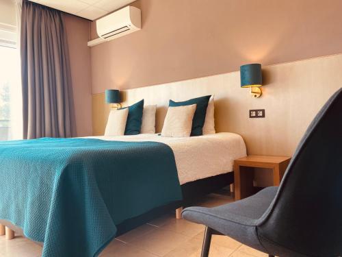 a bedroom with a bed with a blue blanket and a chair at Hotel Rooms in Breskens