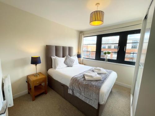 a bedroom with a large bed and a window at Blue Sky Apartments @Wallis Square, Farnborough in Farnborough