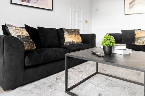 a living room with a black couch and a table at Modern Four Bed House - Parking - Garden - Netflix 802W in Birmingham