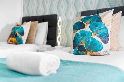 a bedroom with two beds with blue and white pillows at Modern Four Bed House - Parking - Garden - Netflix 802W in Birmingham
