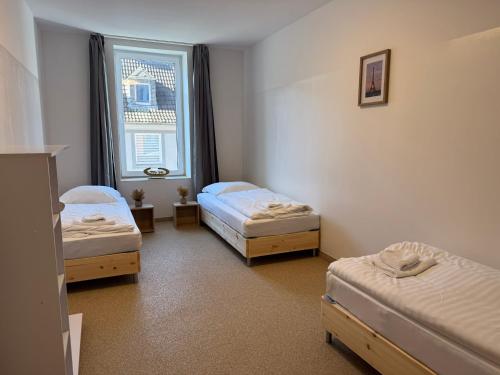 a room with three beds and a window at T&K Apartments - Herne - comfortable 1-3 room apartments in Herne