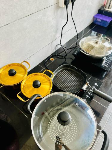 a stove top with three pans and a strainer at The Rina Homestay-Whole Villa with Private Pool,BBQ & Karaoke-Near Beach- in Port Dickson