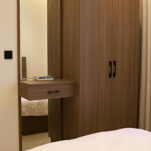 a bedroom with a wooden cabinet with a mirror at BHomed Shaab in Kuwait