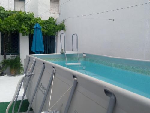a swimming pool with chairs and an umbrella at LA CASA AZUL -Mancha Real, Jaen, Úbeda, Baeza- in Mancha Real