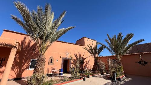 a building with palm trees in front of it at Gite d'étape nomade in Tajda