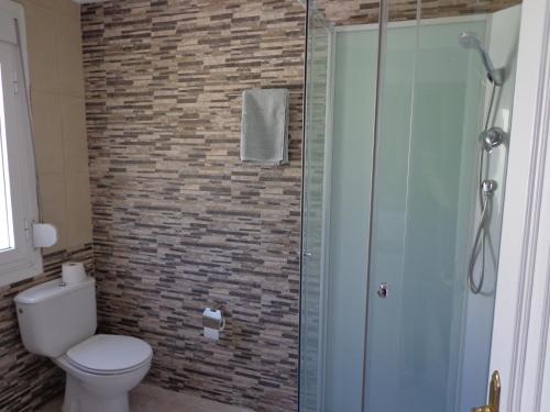 a bathroom with a toilet and a glass shower at Albergue Aqua Portomarin in Portomarin