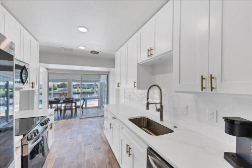 a kitchen with white cabinets and a sink and a table at MAD510 Punta Gorda Isles in Punta Gorda