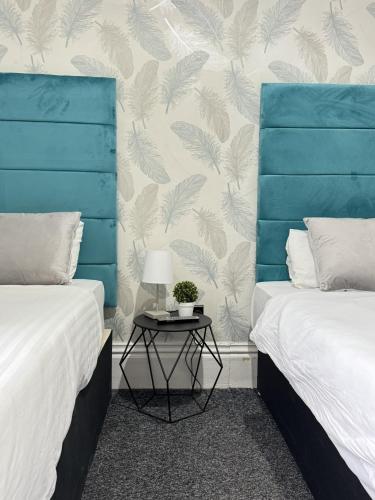 a bedroom with two beds and a table with a lamp at Marine Parade Hotel by PLI in Eastbourne