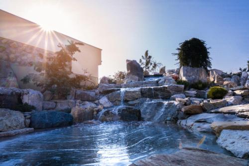 a pool with a waterfall in a backyard with rocks at Pensiunea Parâng in Târgu Jiu
