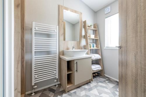 a bathroom with a sink and a mirror at Tranquil Woodland Lodge Retreat in Lincolnshire in Woodhall Spa