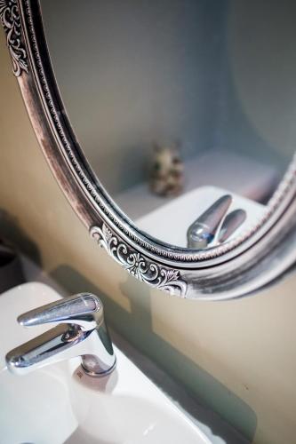 a bathroom sink with a silver mirror and a sink at OFIOYSA KaGa kythnosuites in Mérikhas