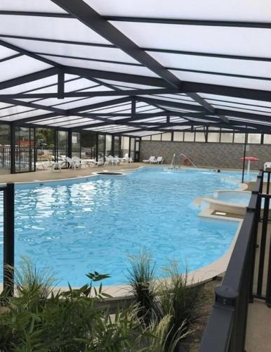 une grande piscine avec toit dans l'établissement Bungalow convivial à Saint-Arnoult avec piscine, à Saint-Arnoult