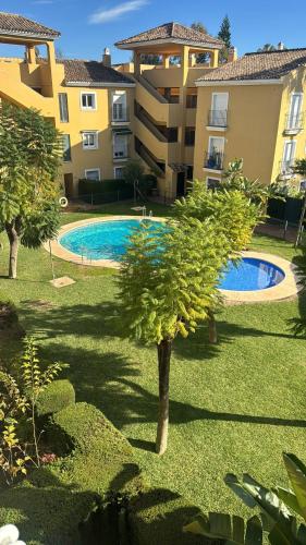 a swimming pool in a yard next to a building at Cozy Room in Modern Shared Apartment in Atalaya, Spain in Estepona