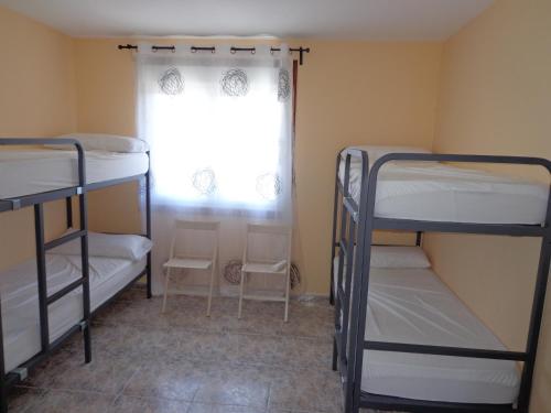 a room with three bunk beds and a window at Albergue Aqua Portomarin in Portomarin