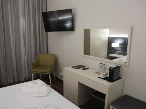a hotel room with a bed and a desk and a mirror at Hotel Lara in Valença