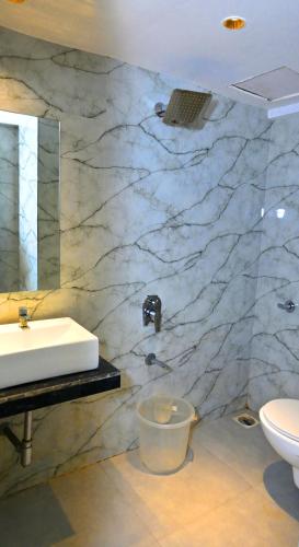 a bathroom with a white sink and a toilet at Hotel Preston Inn in Mumbai