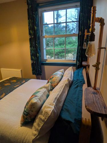 a bedroom with a bed with pillows and a window at Tullochard House B&B in Dunvegan