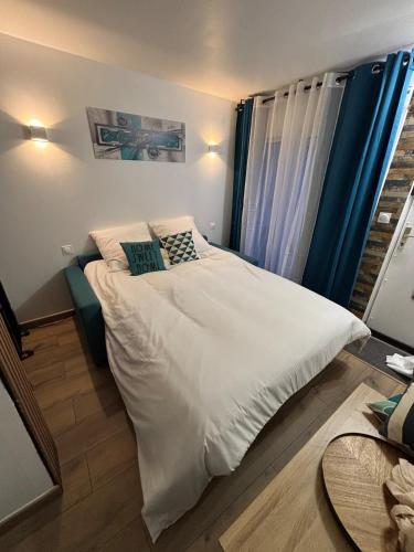 Un dormitorio con una cama con sábanas y almohadas blancas. en Agréable studio avec terrasse, en Rouen