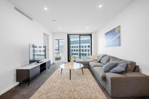 a living room with a couch and a table at Modern City 2B&2B Retreat Await in Canberra