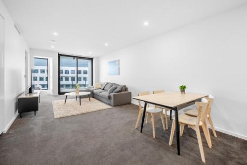 a living room with a table and a couch at Modern City 2B&2B Retreat Await in Canberra
