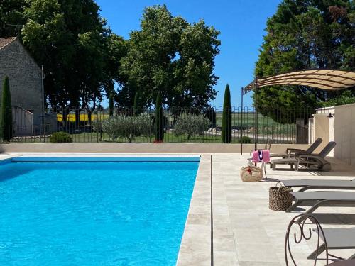 une piscine avec deux chaises et un parasol dans l'établissement Tilleul - Laurier gite rural du Domaine de Laforest, à Fontvieille