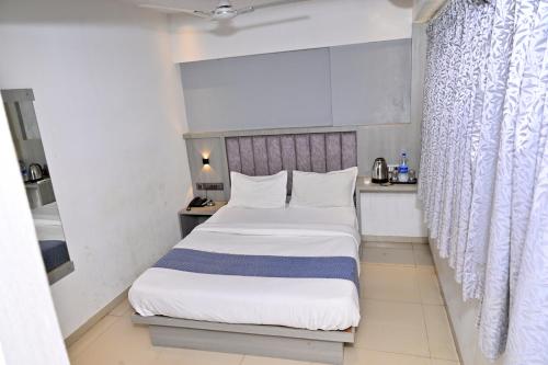 a bedroom with a large bed with white sheets at Hotel Preston Inn in Mumbai