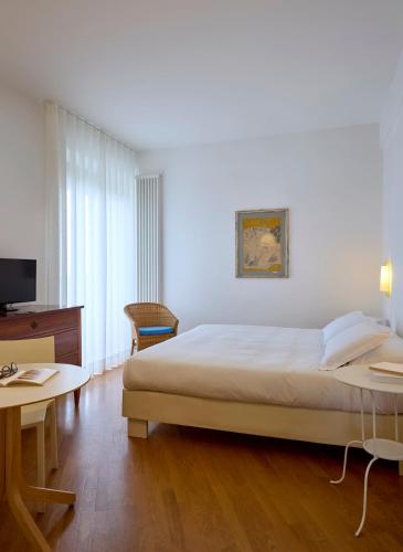 a bedroom with a bed and a desk and a television at Hotel Emilia in Ancona