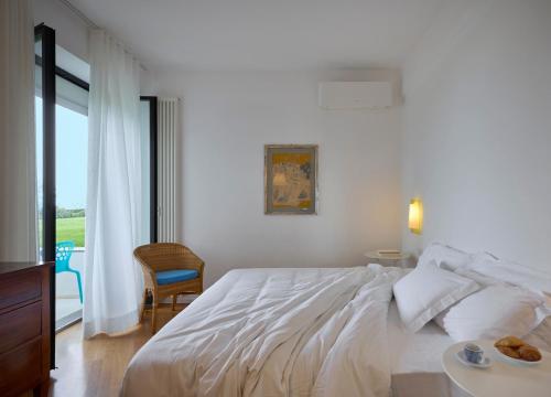 a white bedroom with a large bed and a window at Hotel Emilia in Ancona