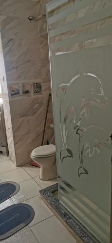 a bathroom with a toilet and a glass door with a dog sticker at شقه فندقيه لوكس in Cairo