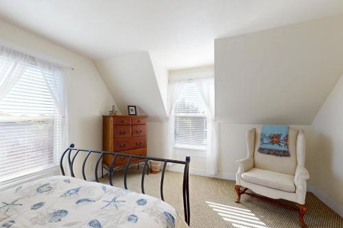 a bedroom with a bed and a chair and windows at Bella Mare in Elk