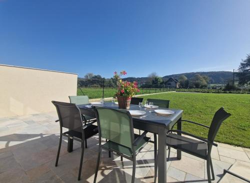a dining table and chairs on a patio at Gite de La Forge in Sébrazac