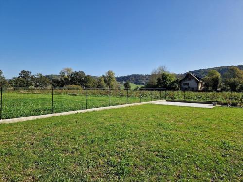 a field of grass with a fence and a house at Gite de La Forge in Sébrazac