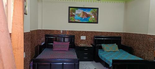 a bedroom with two beds and a picture on the wall at Mountain green valley homestay in Lansdowne