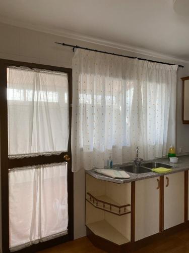 a kitchen with a sink and a window with curtains at Pasaje Solivar in Villanueva del Trabuco
