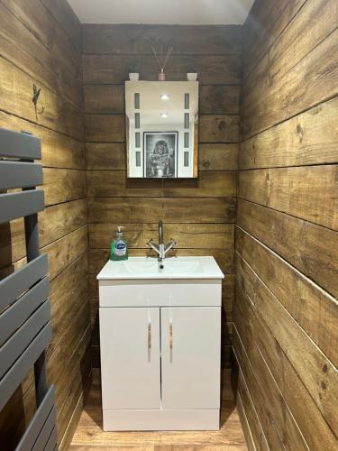 a bathroom with a white sink and wooden walls at Aiskew Villa Annex in Bedale