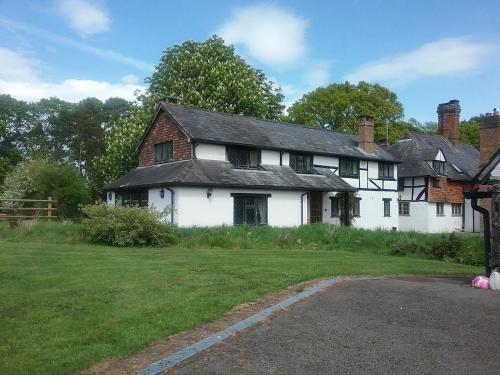 an old white house with a grass yard at Redlands cottage self check in! in West Chiltington