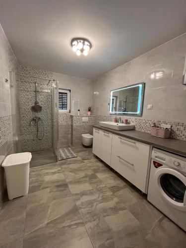 a bathroom with a shower and a sink and a washing machine at Apartman TESSA in Vela Luka