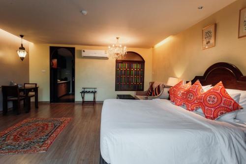 a bedroom with a large white bed with red pillows at SHEIK ISTANA HOTEL CHIANGMAl in Chiang Mai