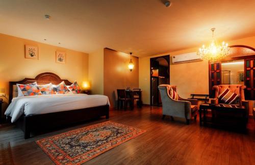 a bedroom with a bed and a living room at SHEIK ISTANA HOTEL CHIANGMAl in Chiang Mai